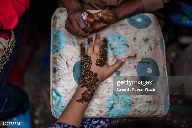 An Indian artists applies henna on the hands of Kashmiri Muslim girls before the upcoming Muslim festival Eid al-Adha on July 31, 2020 in Srinagar,...