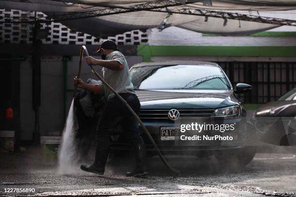 Workers of a car wash carry out their tasks using face masks as a preventive measure in Buenos Aires, Argentina, on July 31, 2020. After more than...