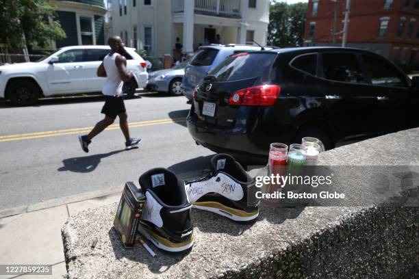 Jogger passes by a pair of sneakers near the 100 block of Adams Street near Ronan Park, where items were left as pat of a make-shift memorial in...