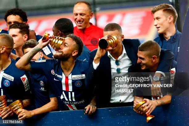 Paris Saint-Germain's French forward Kylian Mbappe and Paris Saint-Germain's Brazilian forward Neymar jokes with their trophies past teammates as...