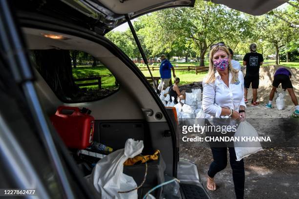 Palmetto Bay's Mayor Karyn Cunningham, puts sand bags in a resident's car trunk in Palmetto Bay near Miami, on July 31, 2020 as Floridians prepare...