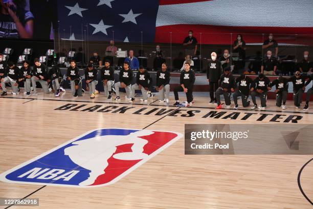 Head coach Gregg Popovich of the San Antonio Spurs stands as other players and staff and the Sacramento Kings kneel around a Black Lives Matters logo...