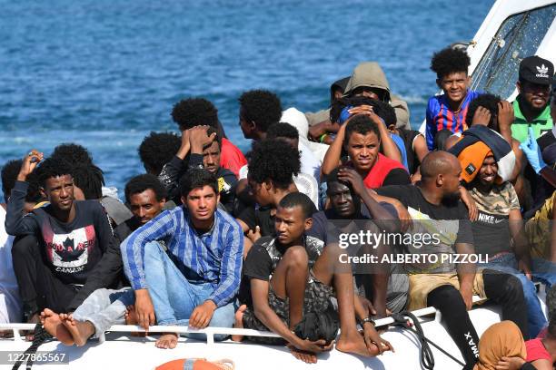 Migrants from Tunisia and Lybia arrive onboard of an Italian Guardia Costiera boat in the Italian Pelagie Island of Lampedusa on August 1, 2020.