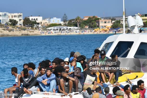 Migrants from Tunisia and Lybia arrive onboard of an Italian Guardia Costiera boat in the Italian Pelagie Island of Lampedusa on August 1, 2020.