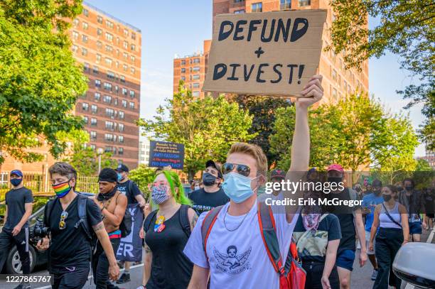 Participant holding a Defund+Divest sign at the protest. Brooklynites gathered at Barclays Center for a march in the streets of Brooklyn, demanding...