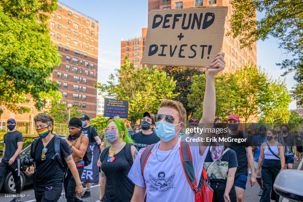 A participant holding a Defund+Divest sign at the protest.