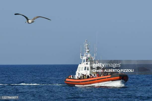 An Italian Guardia Costiera boat with migrants from Tunisia and Lybia arrives in the port of the Italian Pelagie Island of Lampedusa on August 1,...