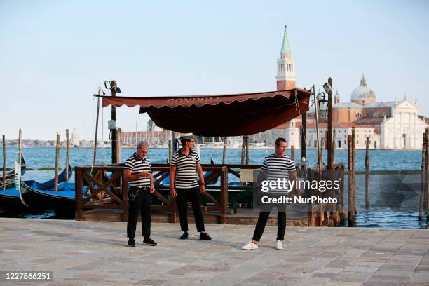 Gondoliers wait customers for a gondola ride on the Grand Canal in Venice, Italy on June 17, 2020. Tourists return in Venice as the country eases its...