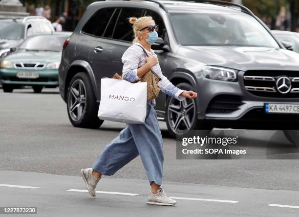 Woman wearing a face mask as a preventive measure walks on the street. Since August 1, 2020 new quarantine rules due the COVID-19 coronavirus are...