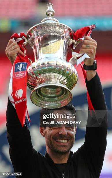 Arsenal's Spanish head coach Mikel Arteta holds the winner's trophy as the team celebrates victory after the English FA Cup final football match...