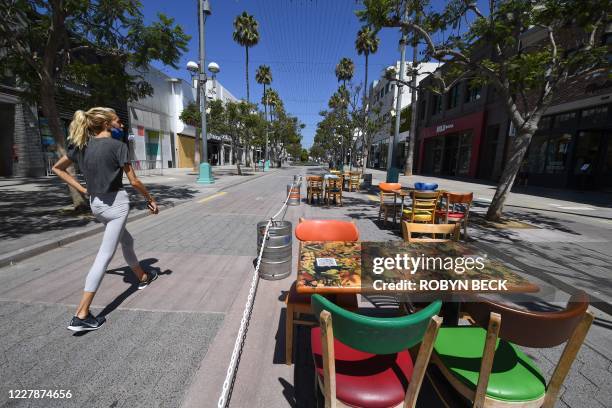 Woman walks down a deserted Third Street Promenade, a usually busy shopping and restaurant pedestrian street in Santa Monica, California, August 1,...