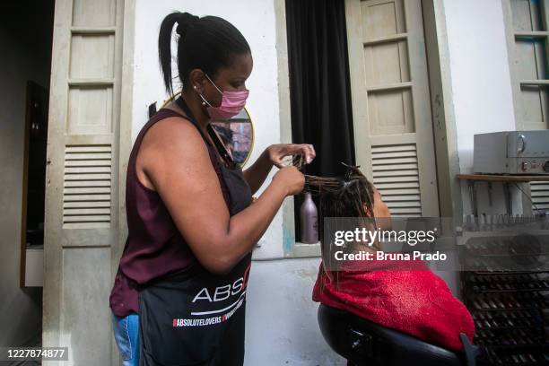 Suzana Coutinho hairdresser and manicurist, dyes a client's hair at the entrance of her own house in the Morro da Coroa favela, in the Santa Teresa...