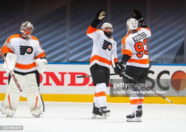 Carter Hart, Nate Thompson and Jakub Voracek of the Philadelphia Flyers celebrate after defeating the Boston Bruins in a Round Robin game during the...
