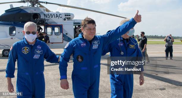 In this handout image provided by NASA, NASA astronaut Robert Behnken gives a thumbs up to onlookers as he boards a plane departing for Houston at...