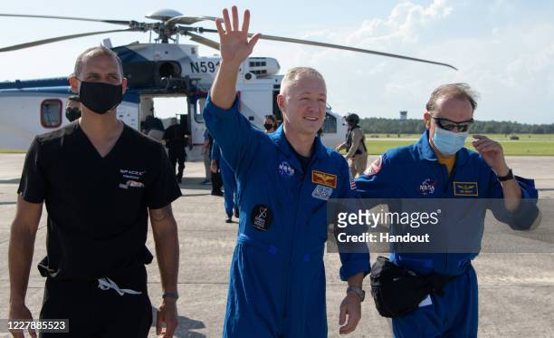 In this handout image provided by NASA, NASA astronaut Douglas Hurley waves to onlookers as he boards a plane departing for Houston at Naval Air...