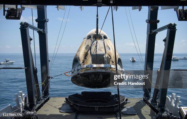 In this handout image provided by NASA, the SpaceX Crew Dragon capsule spacecraft, with NASA astronauts Robert Behnken and Douglas Hurley onboard, is...