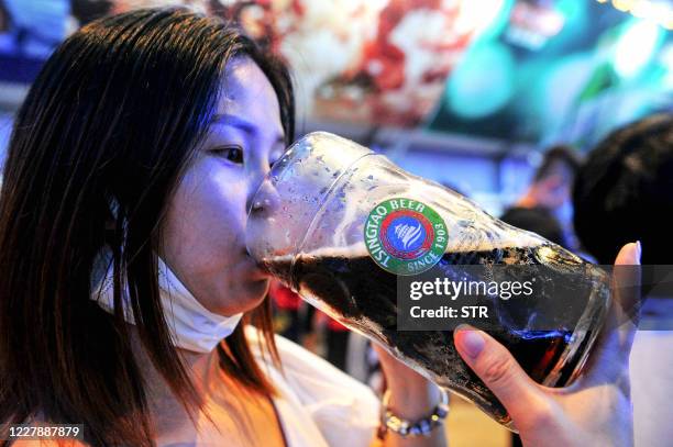 This photo taken on August 1, 2020 shows a woman drinking a beer during the annual Qingdao Beer Festival in Qingdao, in China's eastern Shandong...