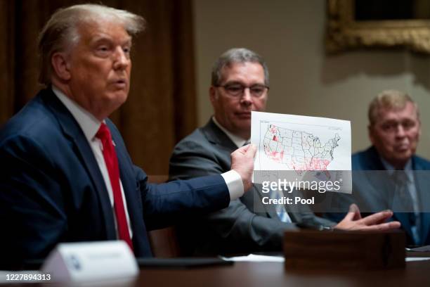 President Donald Trump holds up a map of the coronavirus outbreak while speaking during a meeting with U.S. Tech Workers and signs an Executive Order...