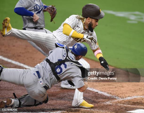 Fernando Tatis Jr. #23 of the San Diego Padres collides with catcher Will Smith of the Los Angeles Dodgers as he's tagged out at the plate during the...