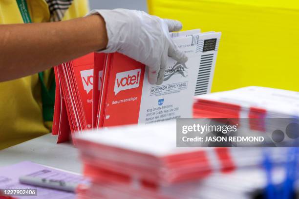 An election worker opens envelopes containing vote-by-mail ballots for the August 4 Washington state primary at King County Elections in Renton,...