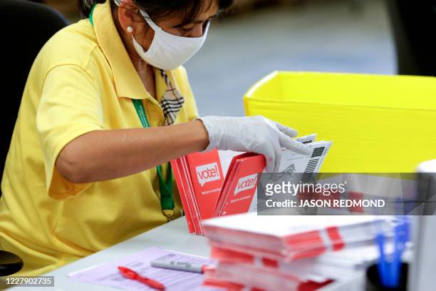 An election worker opens envelopes containing vote-by-mail ballots for the August 4 Washington state primary at King County Elections in Renton,...