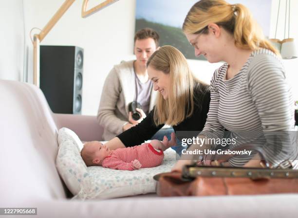 In this photo illustration a midwife is looking at a new born baby at his parents home on March 18, 2019 in Bonn, Germany.