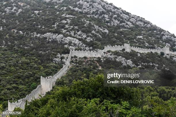 Tourists walk along the walls of Ston, August 4, 2020 in Ston, on Peljesac peninsula on Adriatic. - The south of Croatia, unlike the north, is facing...