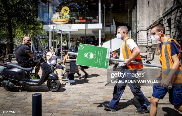 City employees carry a sign with information about mask-wearing obligation on their way to place it on the road Meent in Rotterdam, on August 04 amid...