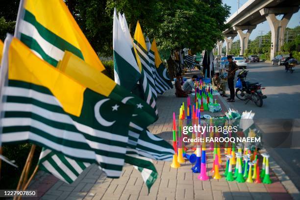 Vendors arrange their merchandise next to Azad Kashmir flags on a roadside stall in Rawalpindi on August 4 ahead of Pakistan's 74th anniversary of...