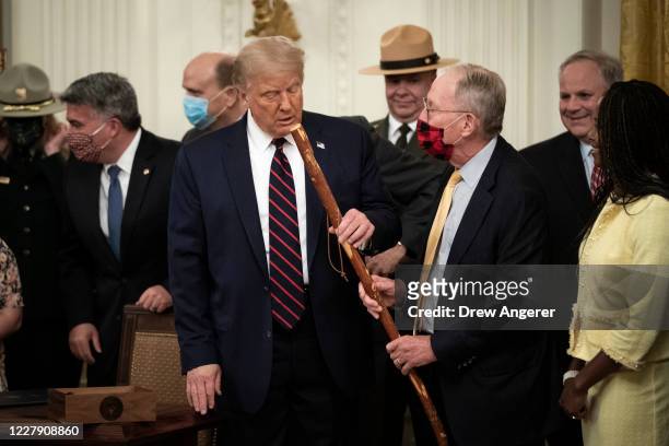 Sen. Lamar Alexander gives U.S. President Donald Trump a walking stick after the president signed the Great American Outdoors Act during a singing...