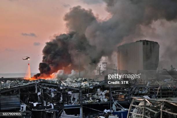 Helicopter puts out a fire at the scene of an explosion at the port of Lebanon's capital Beirut on August 4, 2020.