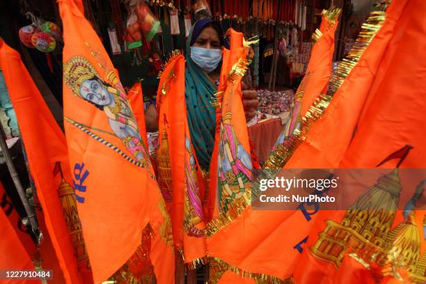 Street vendor wearing protective masks sells religious saffron flags near Hanuman Garhi Temple before the arrival of Prime Minister Narendra Modi for...