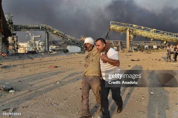 Man carries a wounded person after a fire at a warehouse with explosives at the Port of Beirut led to massive blasts in Beirut, Lebanon on August 4,...