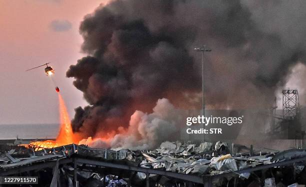 Helicopter puts out a fire at the scene of an explosion at the port of Lebanon's capital Beirut on August 4, 2020.