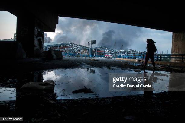 Woman walks toward the port as smoke billows after a large explosion on August 4, 2020 in Beirut, Lebanon. Video shared on social media showed a...