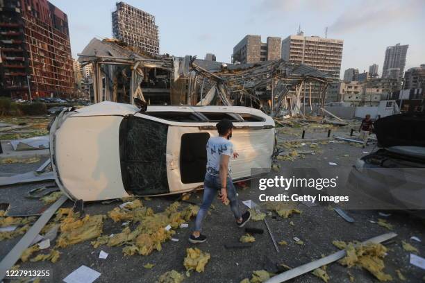 Man walks by an overturned car and destroyed buildings on August 4, 2020 in Beirut, Lebanon. At least 50 people were killed and thousands more...