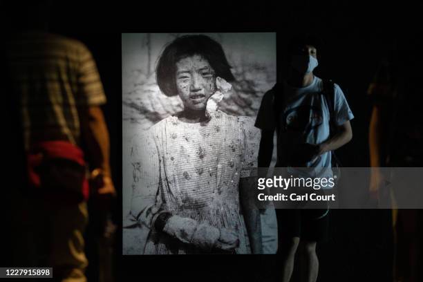 People walk past a photograph of 10-year-old atomic bomb survivor Yukiko Fujii who went on to have two children but died of cancer at the age of 42,...