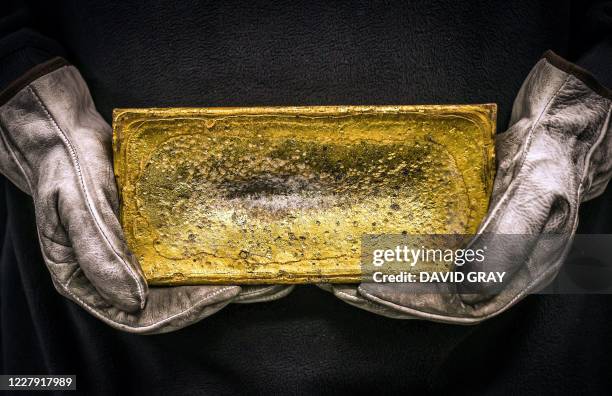 Worker hold a 20 kilogram gold brick at the ABC Refinery in Sydney on August 5, 2020. Gold prices hit 2,000 USD an ounce on markets for the first...