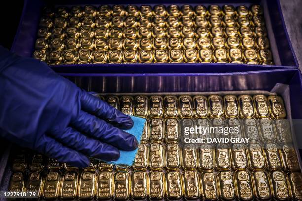 Worker polishes gold bullion bars at the ABC Refinery in Sydney on August 5, 2020. Gold prices hit 2,000 USD an ounce on markets for the first time...