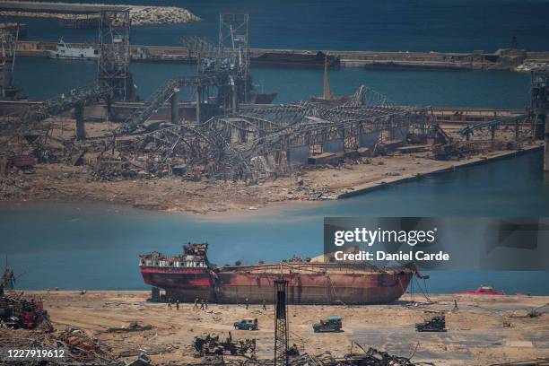 Day after a massive explosion occurred, people walk past a boat that received damages at the port on Aug. 5, 2020 in Beirut, Lebanon. As of Wednesday...