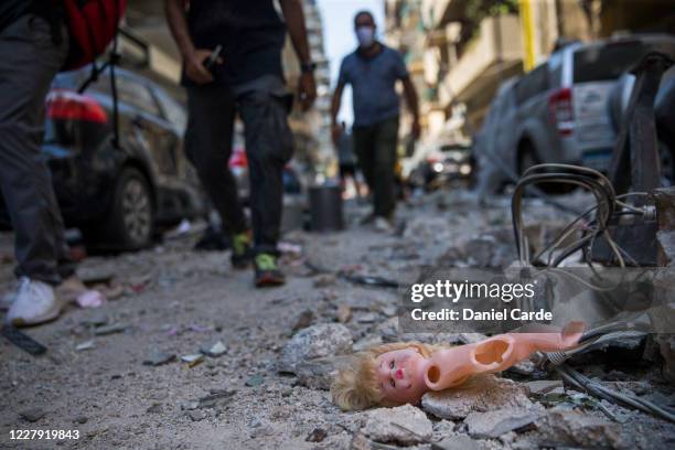 People walk past a childs doll that was blown out of a nearby building after a massive explosion, which occurred a day before, on Aug. 5, 2020 in...