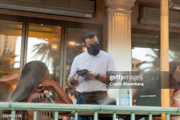 Waiter wearing a protective mask takes an order at HEXX kitchen + bar restaurant at the Caesars Entertainment Inc. Paris Las Vegas hotel and casino...