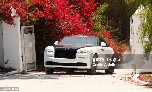 One of several exclusive vehicles departs the scene at Mulholland Drive as LAPD Police investigate the location of the huge home on 13200 Mulholland...