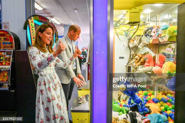 Prince William, Duke of Cambridge and Catherine, Duchess of Cambridge play a grab a teddy game as the Duchess turns to the Duke after picking up a...