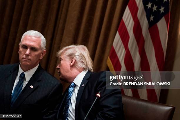 President Donald Trump whispers to US Vice President Mike Pence before a meeting with South Korea's President Moon Jae-in in the Cabinet Room of the...