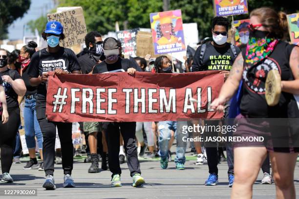 Protestors carry a "Free Them All" banner during a "Defund the Police" march from King County Youth Jail to City Hall in Seattle, Washington on...