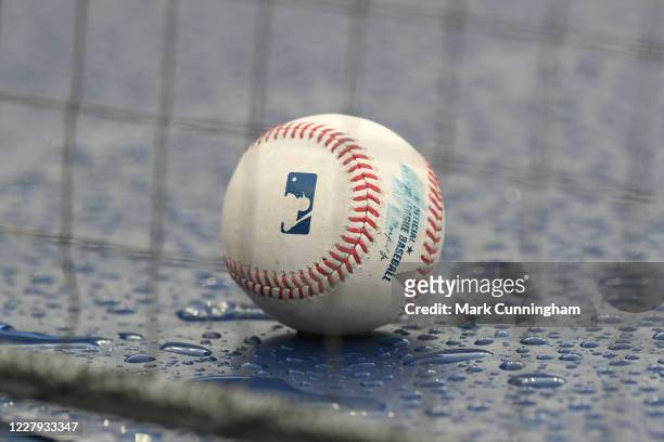 Detailed view of an official Major League baseball sitting on top of the dugout in the rain during game one of a doubleheader between the Cincinnati...