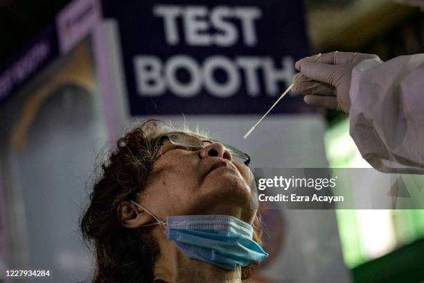 Medical worker conducts a COVID-19 swab test on a resident at a basketball court on August 6, 2020 in Navotas city, Metro Manila, Philippines....