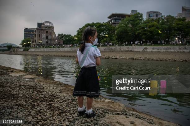 Little girl looks on as lanterns float on the river next to the Atomic Bomb Dome during a ceremony to mark the 75th anniversary of the Hiroshima...