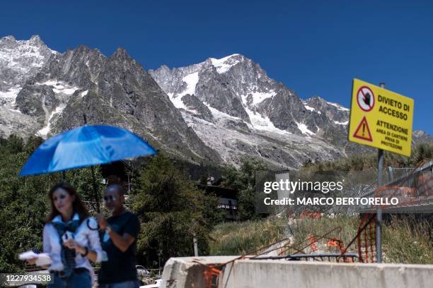 Journalists work next to a sign reading "Access denied" in front of the Planpincieux glacier in the village of La Palud, in Courmayeur, Val Ferret,...